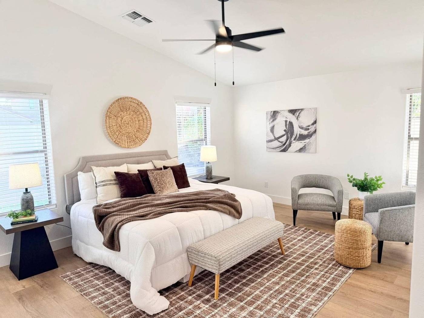 Primary bedroom staged with white bedding, a brown throw and woven wall decor in Gilbert, AZ Primary bedroom staged with white bedding, a brown throw and woven wall decor in Gilbert, AZ